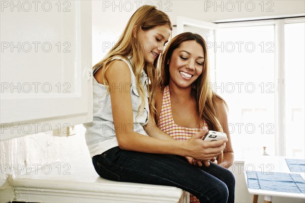 Native American mother and daughter using cell phone