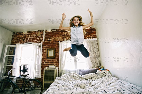 Native American girl jumping on bed