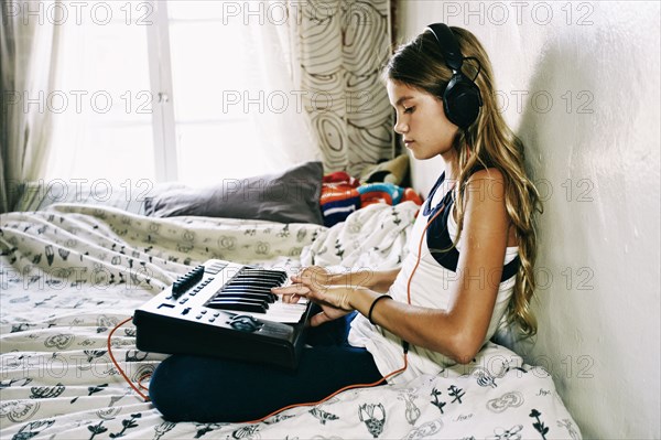 Native American girl playing keyboard on bed