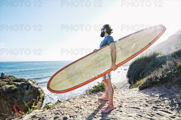 Caucasian man holding surfboard at beach