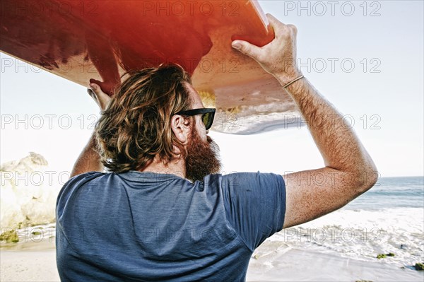 Caucasian man holding surfboard at beach