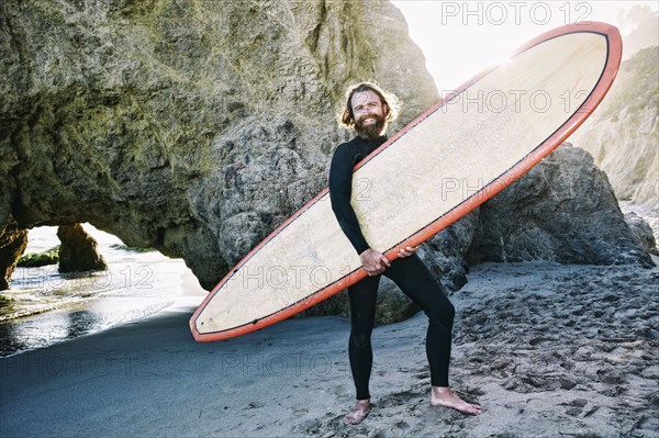Caucasian man holding surfboard at beach