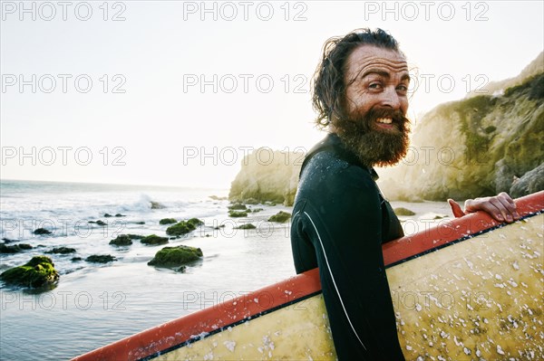 Caucasian man holding surfboard at beach