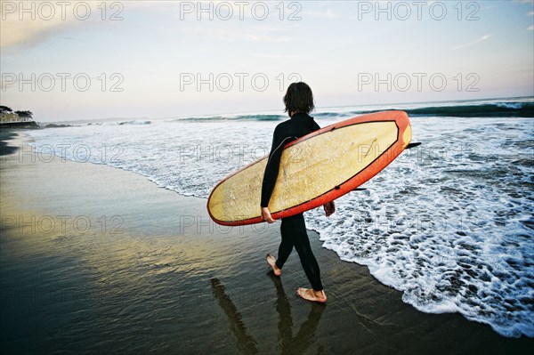 Caucasian man carrying surfboard at beach
