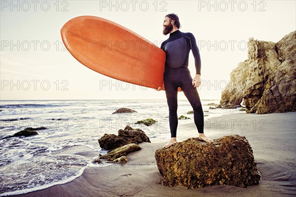 Caucasian man holding surfboard at beach