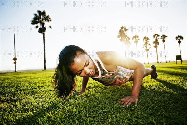 Mixed race athlete doing push-ups in park