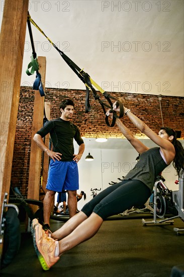 Woman working out with trainer in gymnasium