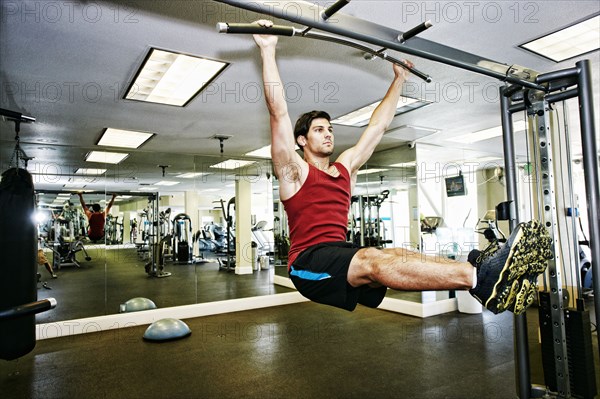 Man doing pull-ups in gymnasium