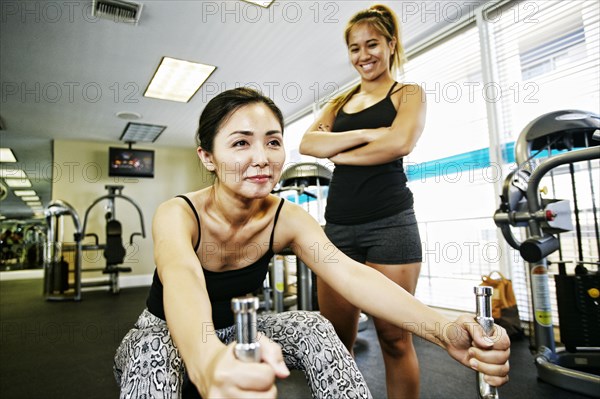 Woman working out with trainer in gymnasium