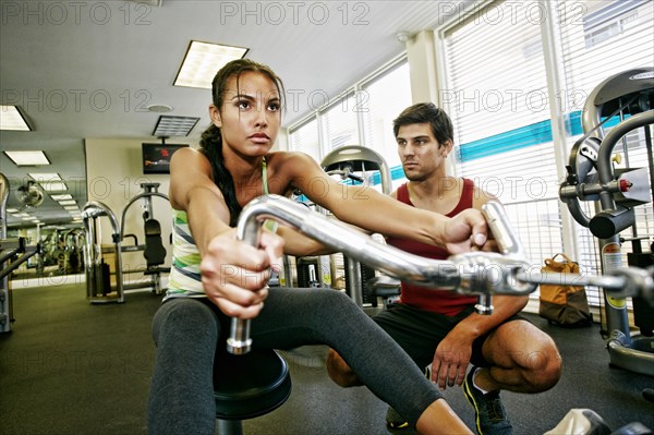 Woman working out with trainer in gymnasium