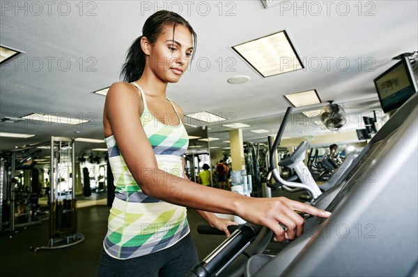 Mixed race woman using treadmill in gymnasium