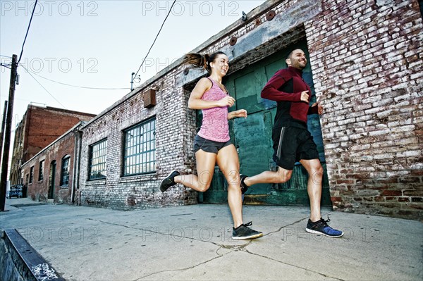 Caucasian couple jogging on sidewalk