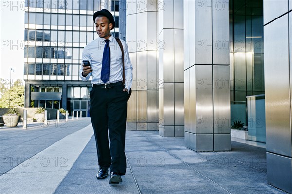 Black businessman using cell phone outside office building