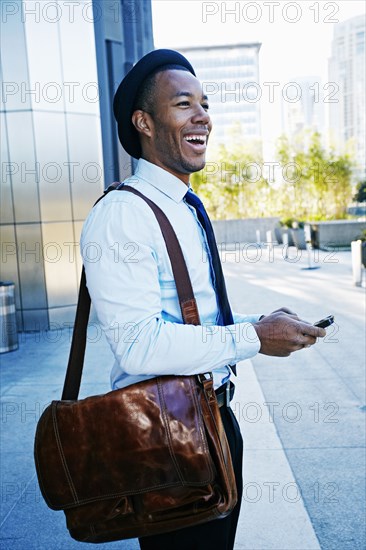 Black businessman using cell phone outside office building