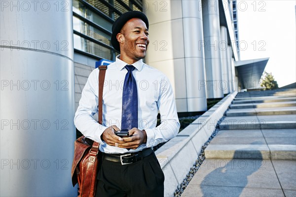 Black businessman using cell phone outside office building