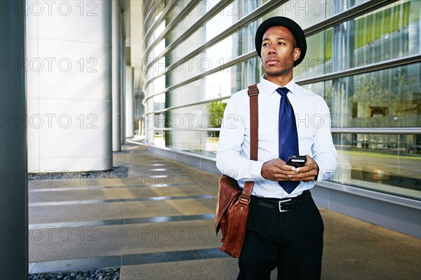 Black businessman using cell phone outside office building