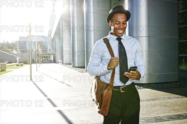 Black businessman using cell phone outside office building