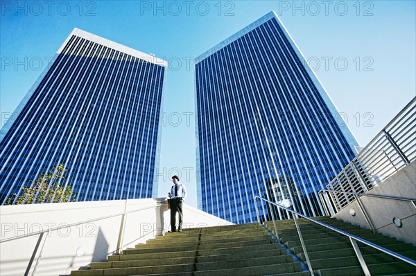 Black businessman standing under highrise buildings