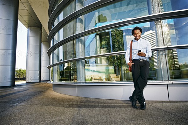 Black businessman using cell phone outside office building