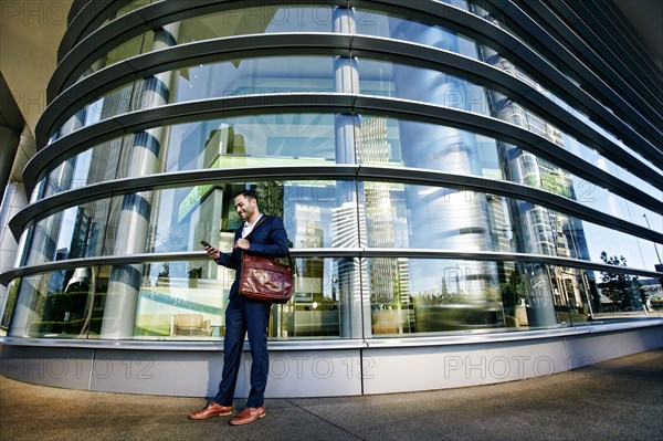 Black businessman using cell phone outside office building