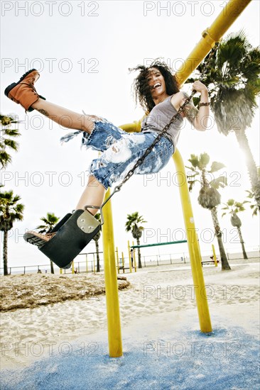 Mixed race woman standing on swing at beach