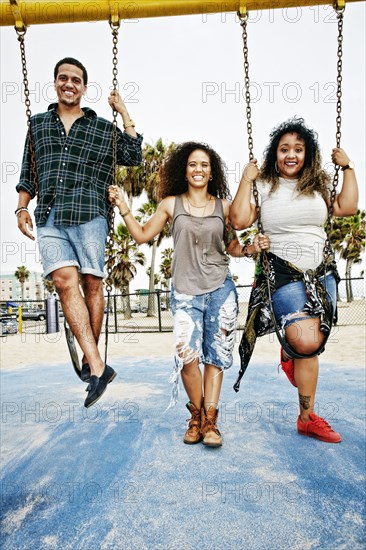 Friends playing on swings at beach