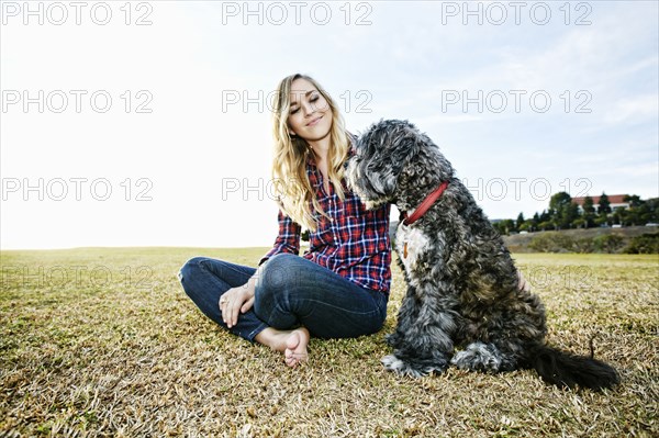 Caucasian woman and dog sitting in park