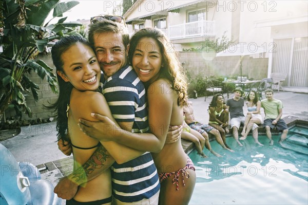 Friends hugging near swimming pool