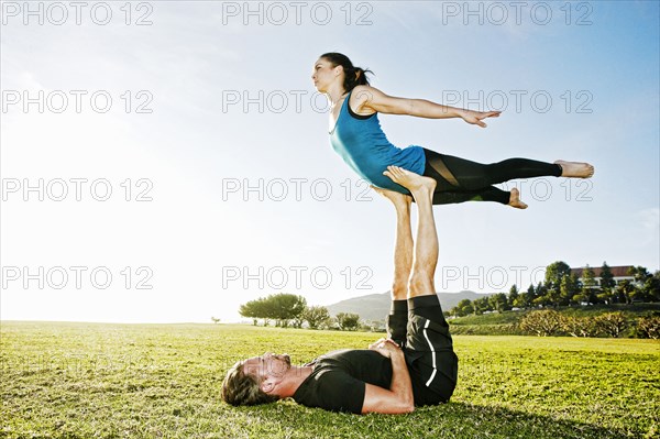 Caucasian couple doing acro yoga in park