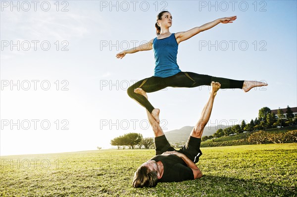 Caucasian couple doing acro yoga in park