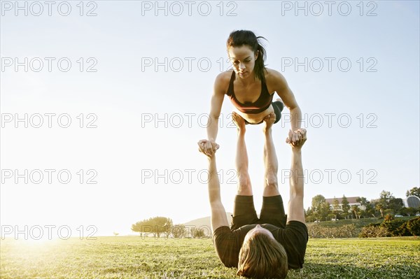 Caucasian couple doing acro yoga in park