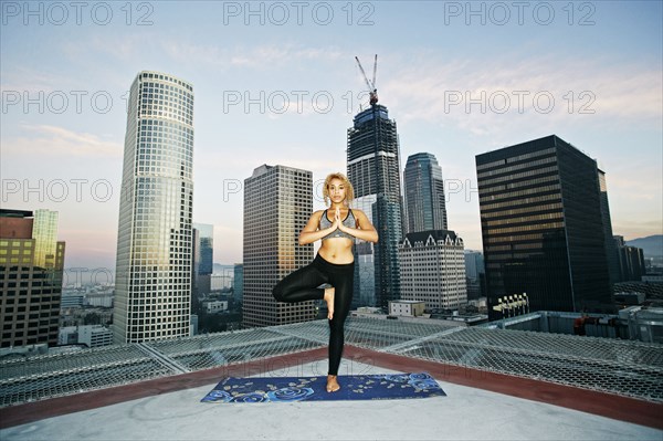 Mixed race woman practicing yoga on urban rooftop