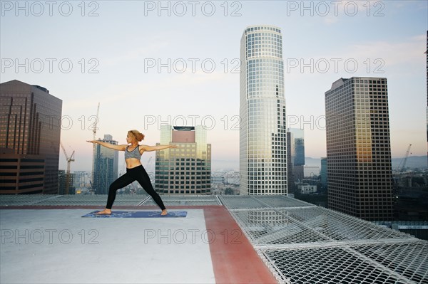 Mixed race woman practicing yoga on urban rooftop