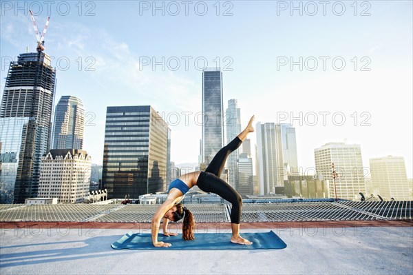 Mixed race woman practicing yoga on urban rooftop