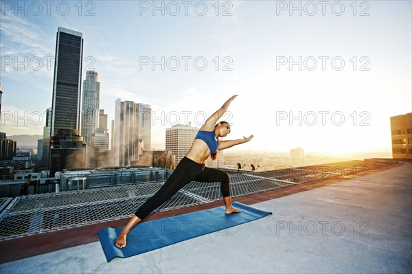 Mixed race woman practicing yoga on urban rooftop