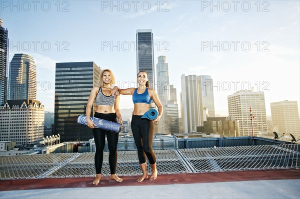 Women holding yoga mats on urban rooftop