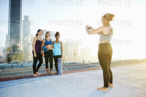 Woman photographing friends on urban rooftop
