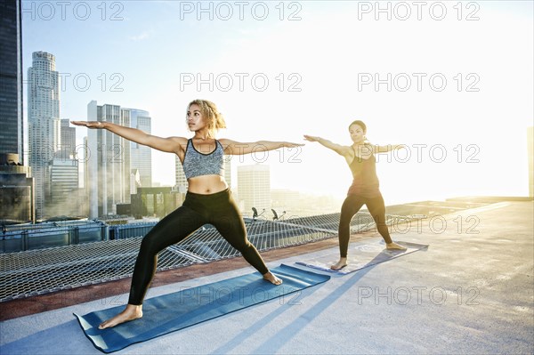 Women practicing yoga on urban rooftop