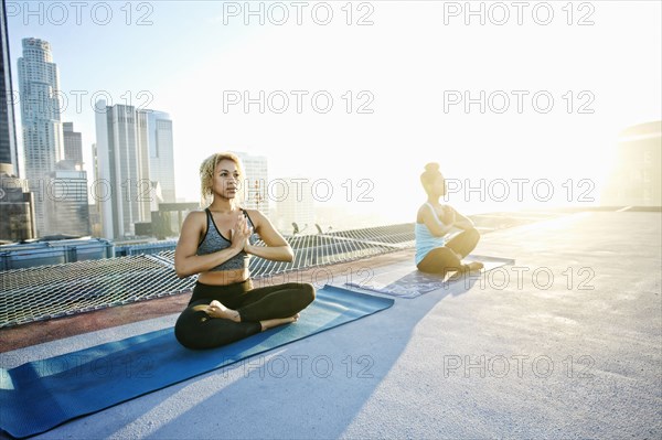 Women practicing meditating on urban rooftop