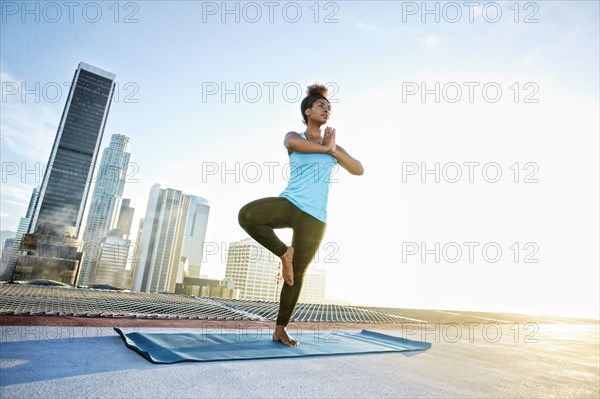 Black woman practicing yoga on urban rooftop