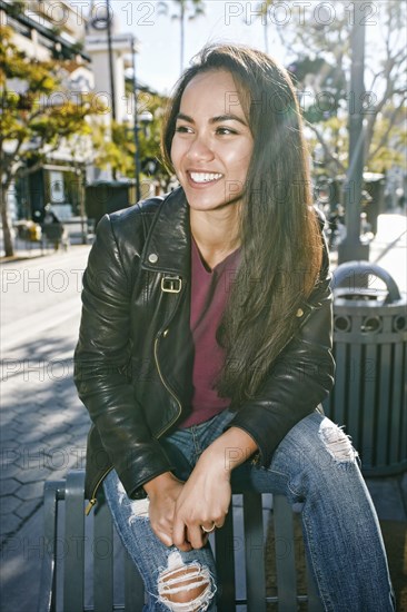 Asian woman sitting on city bench