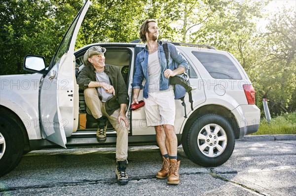 Caucasian sitting and standing at car