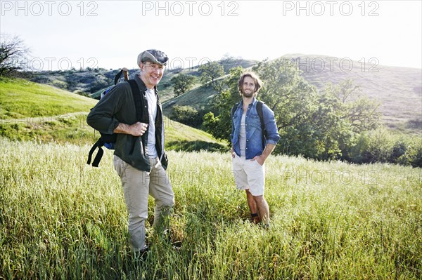 Caucasian hikers standing in grass on mountain