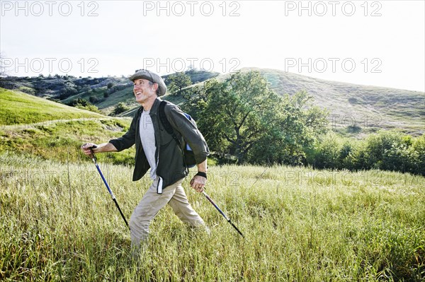 Caucasian man hiking in grass on mountain