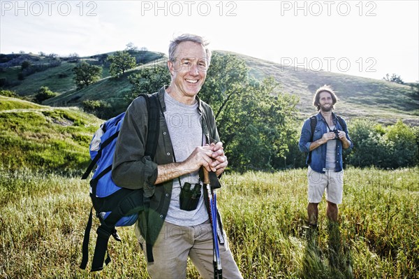 Caucasian hikers standing in grass on mountain