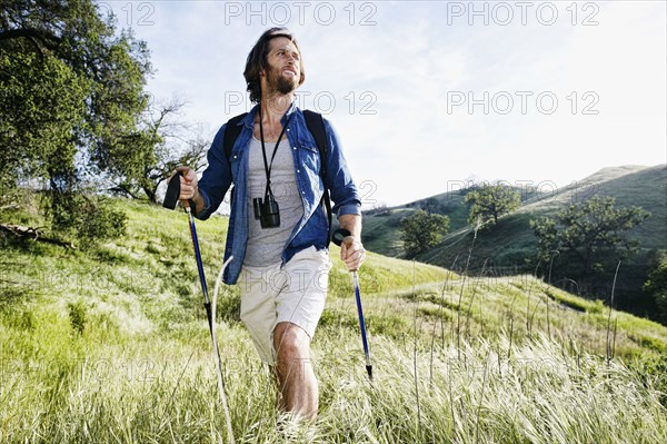 Caucasian man hiking in grass on mountain