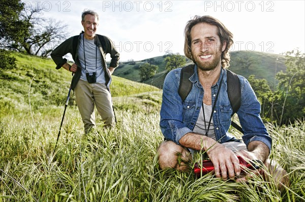 Caucasian hikers resting in grass on mountain