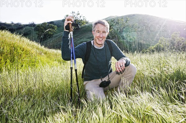 Caucasian hiker kneeling in grass on mountain