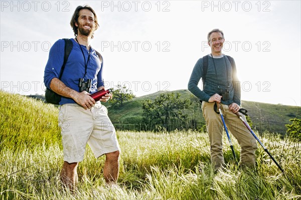 Caucasian hikers standing in grass on mountain