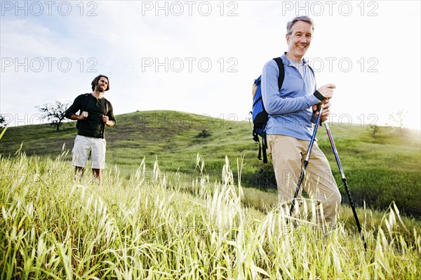 Caucasian men hiking in grass on mountain